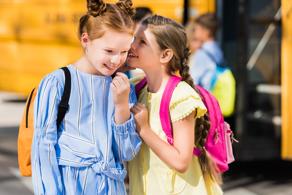 かわいい小さな女子生徒の学校のバスの前でおしゃべり ロイヤリティフリー写真 画像素材