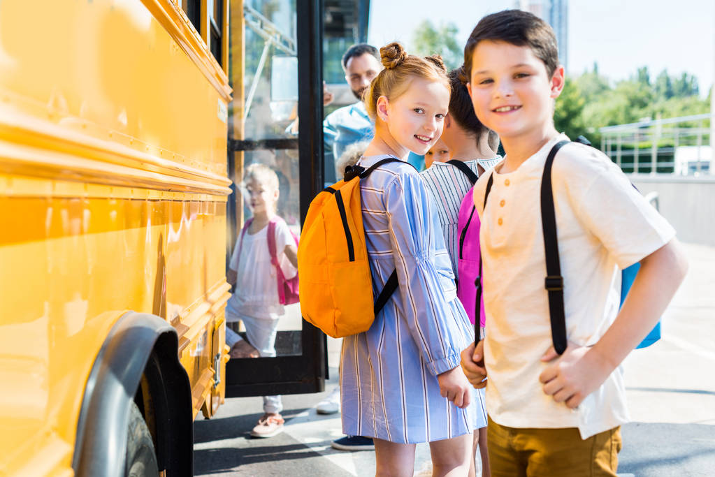 χαρούμενοι λίγο μαθητές εισέρχονται σχολικό λεωφορείο με τους συμμαθητές - Φωτογραφία, εικόνα