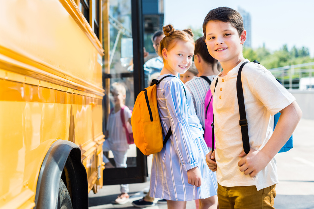 petits élèves souriants entrant dans le bus scolaire avec leurs camarades de classe
 - Photo, image
