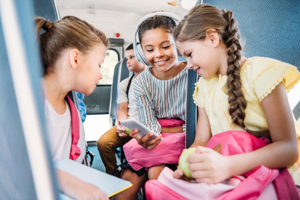 група чарівних школярки використовують смартфон разом під час їзди на шкільному автобусі
 - Фото, зображення