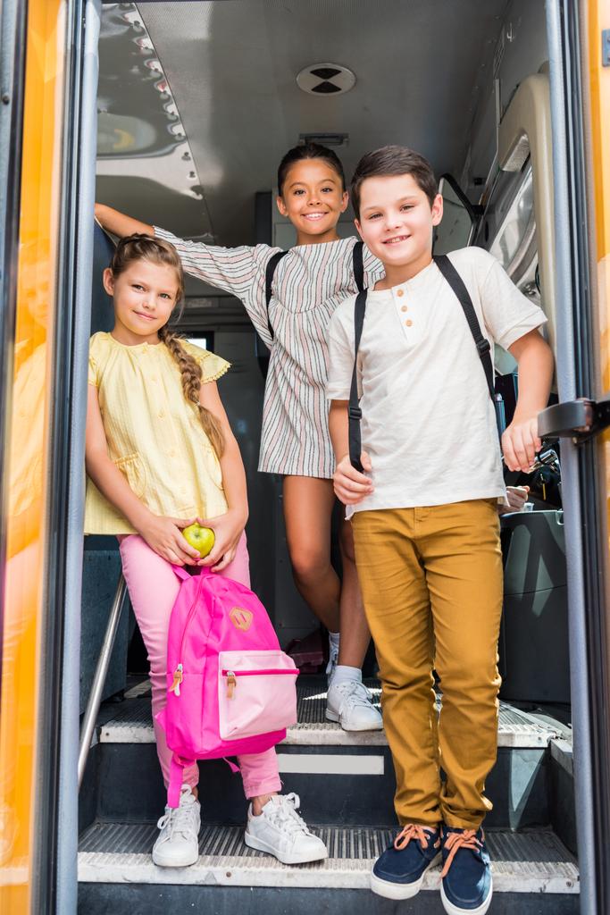 ryhmä hymyileviä koululaisia seisoo koulubussissa
 - Valokuva, kuva