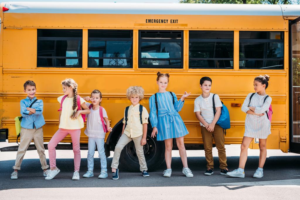 ομάδα χαρούμενοι μαθητές θέτουν μπροστά από το σχολικό λεωφορείο - Φωτογραφία, εικόνα