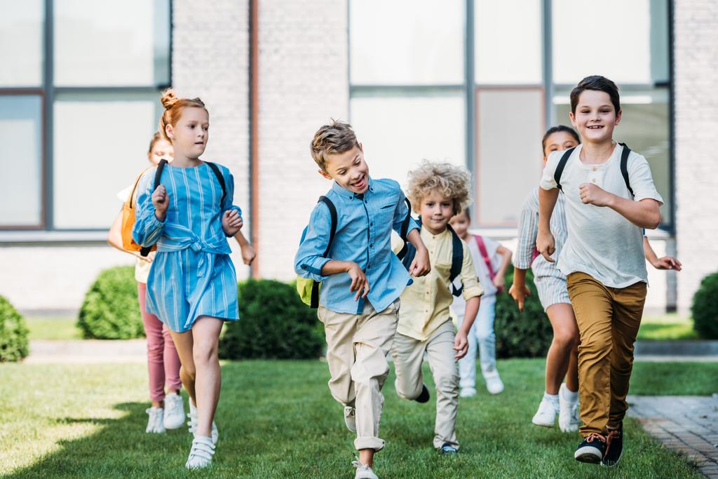 groep gelukkige leerlingen runing door schooltuin - Foto, afbeelding