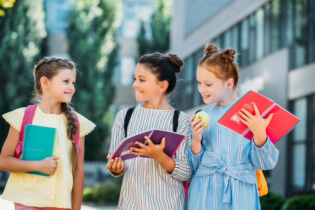 Gruppe glücklicher Schulmädchen mit Notizbüchern, die nach der Schule Zeit miteinander verbringen - Foto, Bild
