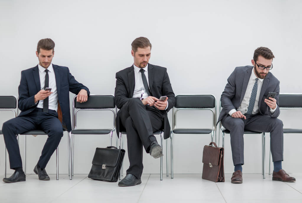 Geschäftsleute mit Mobiltelefonen sitzen im Büroflur - Foto, Bild
