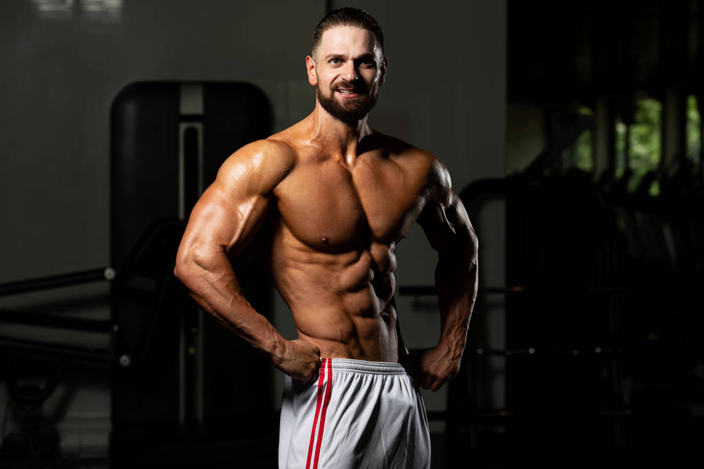 Portret młodego sprawnego fizycznie mężczyzny Pokazywanie dobrze wyszkolonego ciała - Muscular Athletic Bodybuilder Fitness Model pozowanie po ćwiczeniach - Zdjęcie, obraz
