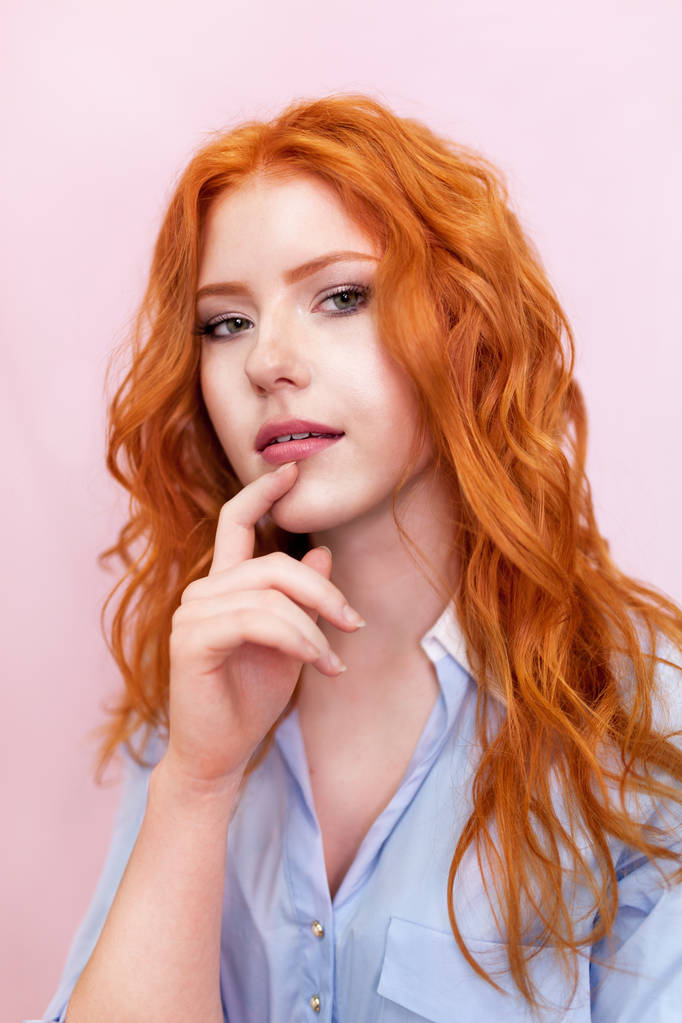 A rózsaszín háttér gyönyörű vörös hajú lány portréja. - Fotó, kép
