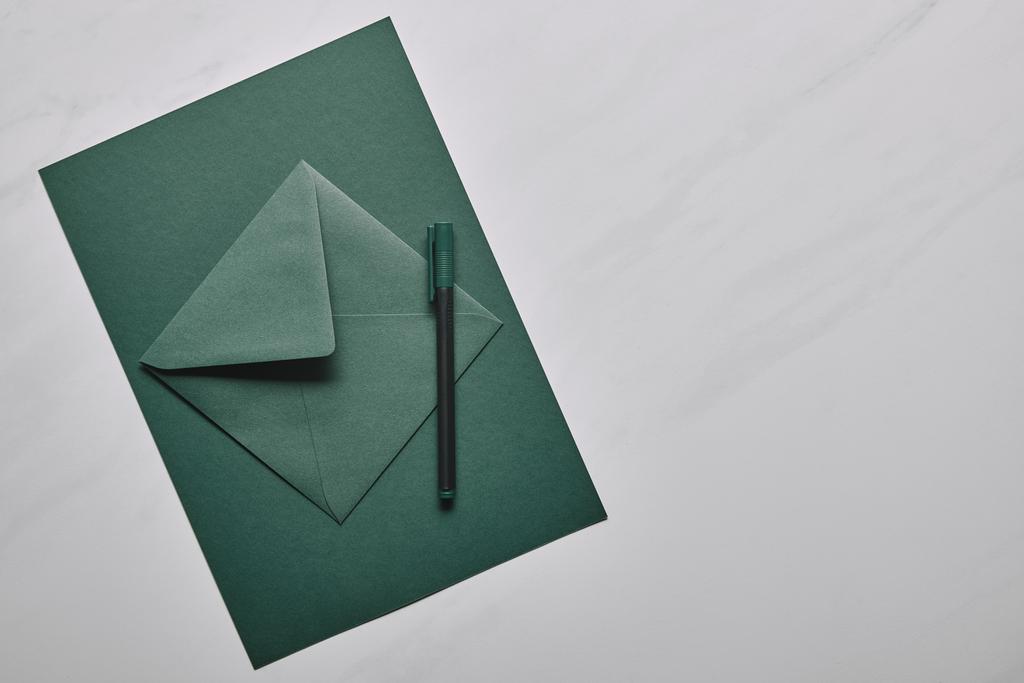 Zelená obálka s perem na bílém mramorovém pozadí - Fotografie, Obrázek