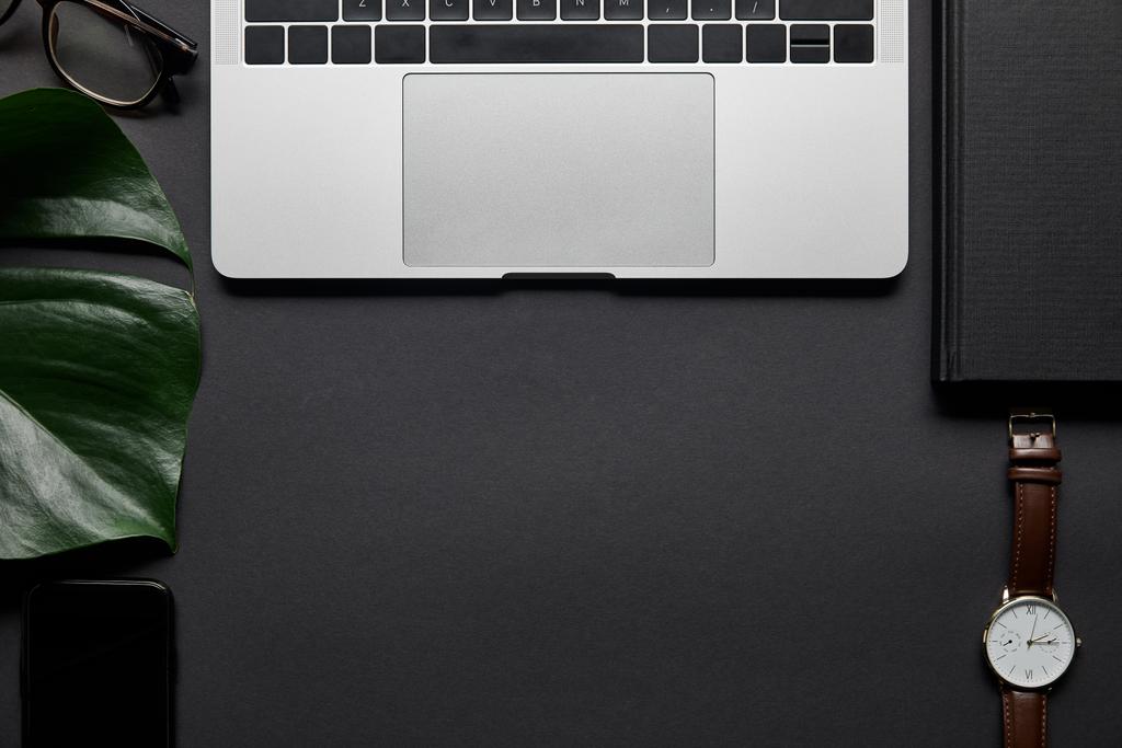 Koostumus kannettavan tietokoneen ja liiketoiminnan tarvikkeet mustalla taustalla
 - Valokuva, kuva