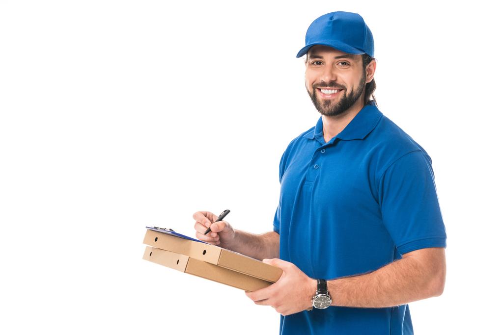 glücklicher Zusteller mit Schachteln mit Pizza-Schrift auf Klemmbrett isoliert auf weiß  - Foto, Bild