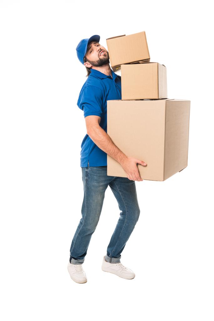 full length view of tired delivery man holding stacked cardboard boxes and looking at camera isolated on white  - Photo, Image