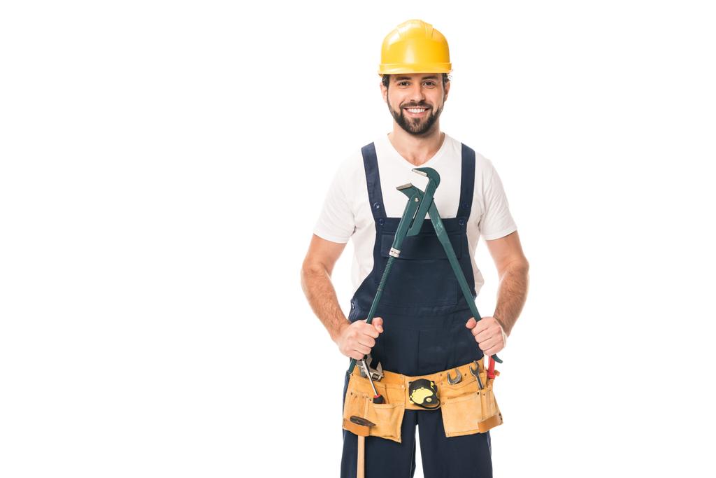 handsome happy repairman in tool belt holding adjustable wrench and smiling at camera isolated on white - Photo, Image