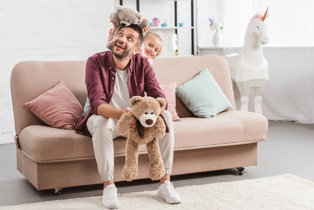 pai e filha brincando com ursinhos de pelúcia no sofá
 - Foto, Imagem