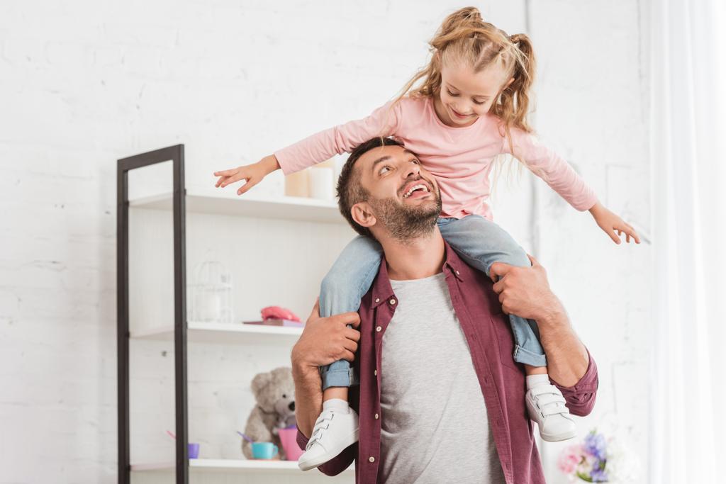 daughter sitting on fathers back and having fun at home - Photo, Image