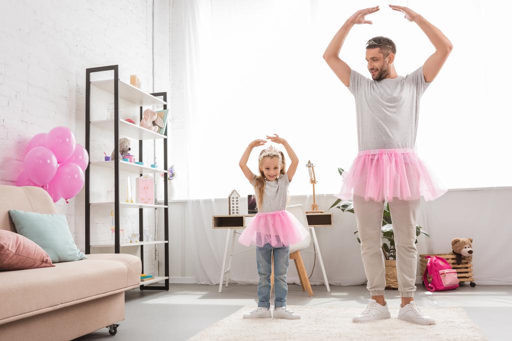 Отец и дочь в розовых юбочках в пачках танцуют как балерины
 - Фото, изображение