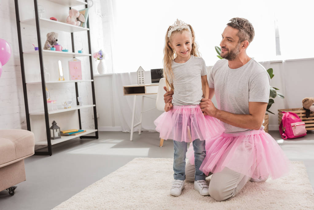 apa és lánya a rózsaszín tutu szoknya mosolyogva otthon - Fotó, kép
