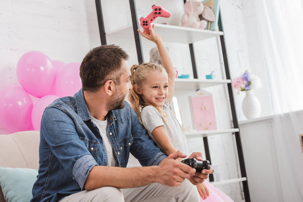 father and daughter having fun and playing with joysticks - Photo, Image