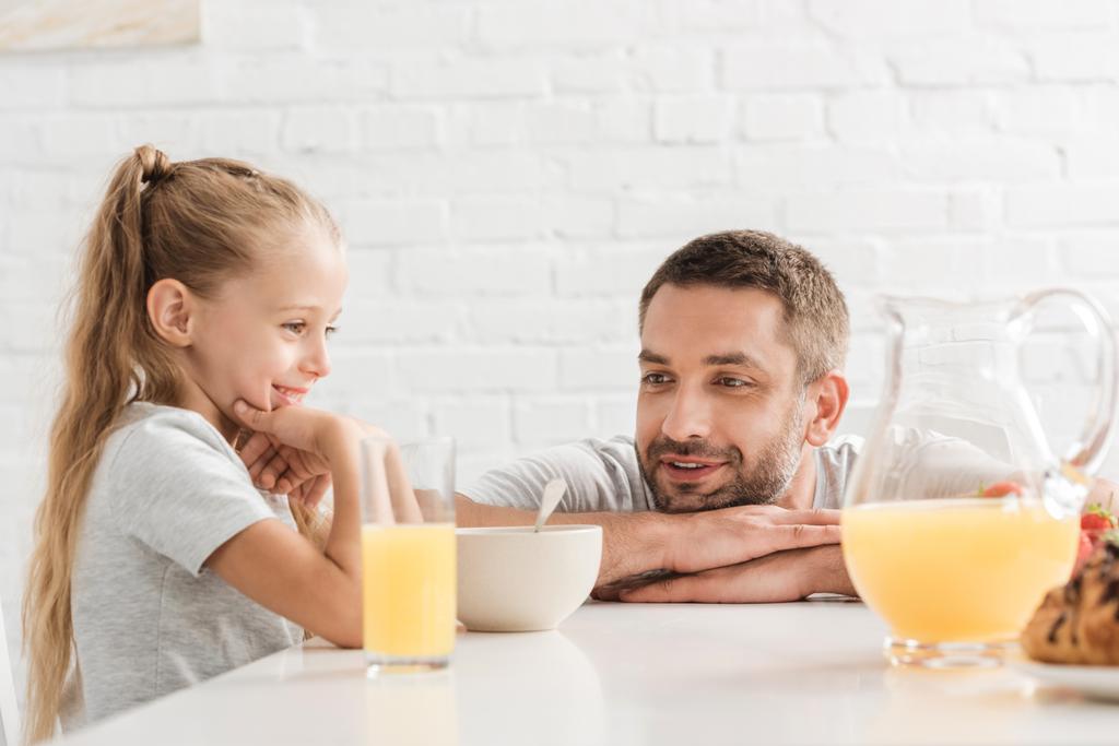 Vater und Tochter trinken Orangensaft in der Küche - Foto, Bild