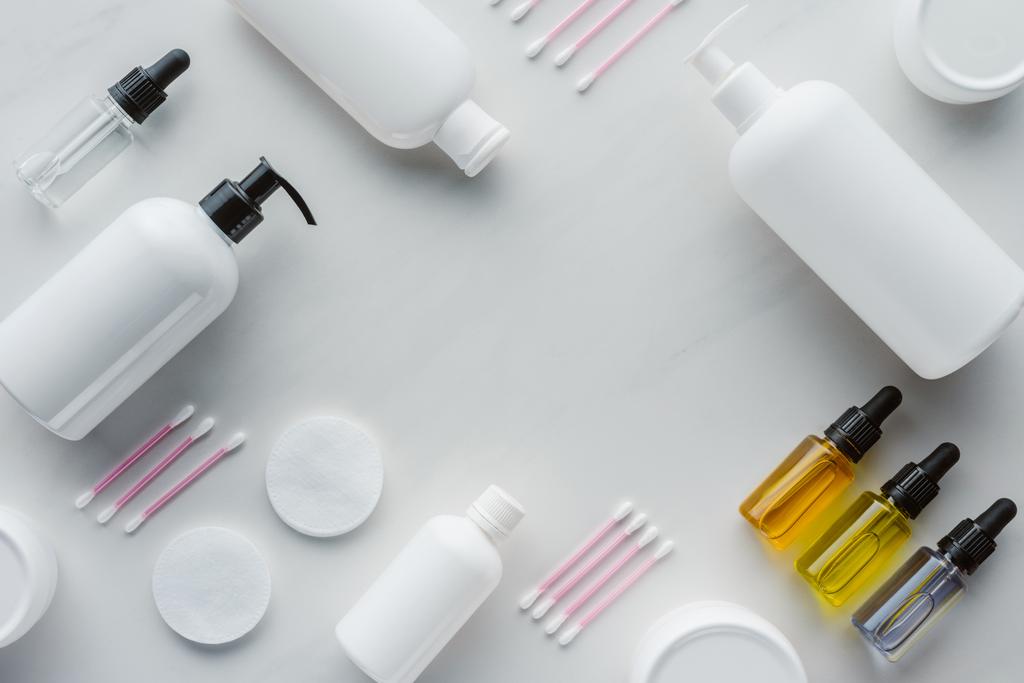 top view of bottles of cream, natural oils and cotton swabs on white tabletop, beauty concept - Photo, Image