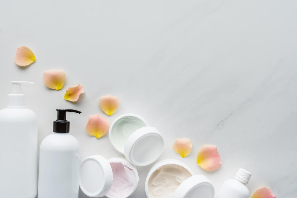 top view of bottles of cream and rose petals on white tabletop, beauty concept - Photo, Image