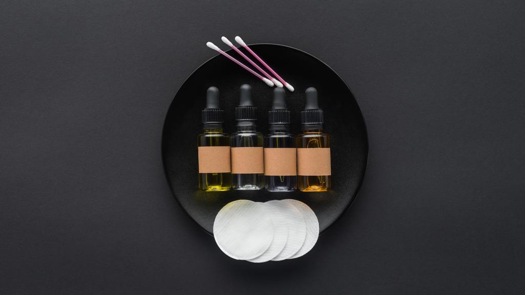 vue du dessus des bouteilles d'huiles naturelles et des tampons cosmétiques sur l'assiette, concept de beauté
 - Photo, image