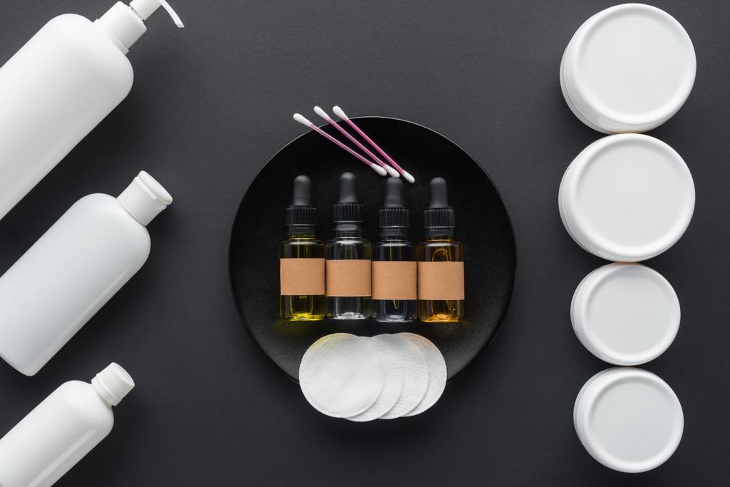 vista superior de botellas de crema, aceites naturales y almohadillas cosméticas aisladas en negro, concepto de belleza
 - Foto, imagen