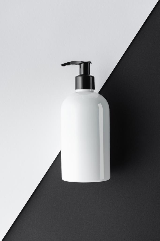 bovenaanzicht van fles crème op zwart-wit oppervlak, beauty concept - Foto, afbeelding