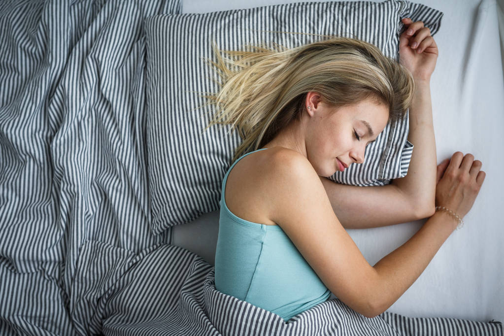 Όμορφη νεαρή γυναίκα που κοιμάται στο κρεβάτι (τονισμένο χρώμα εικόνα, ρηχά Dof) - Φωτογραφία, εικόνα