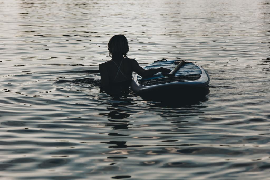 силуэт женщины, плавающей в воде с доской для супа
   - Фото, изображение