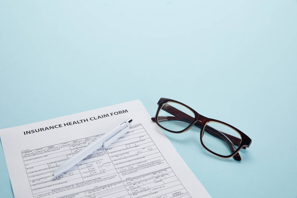 lähikuva vakuutuksesta sairausvakuutuslomake, kynä ja silmälasit sininen
 - Valokuva, kuva