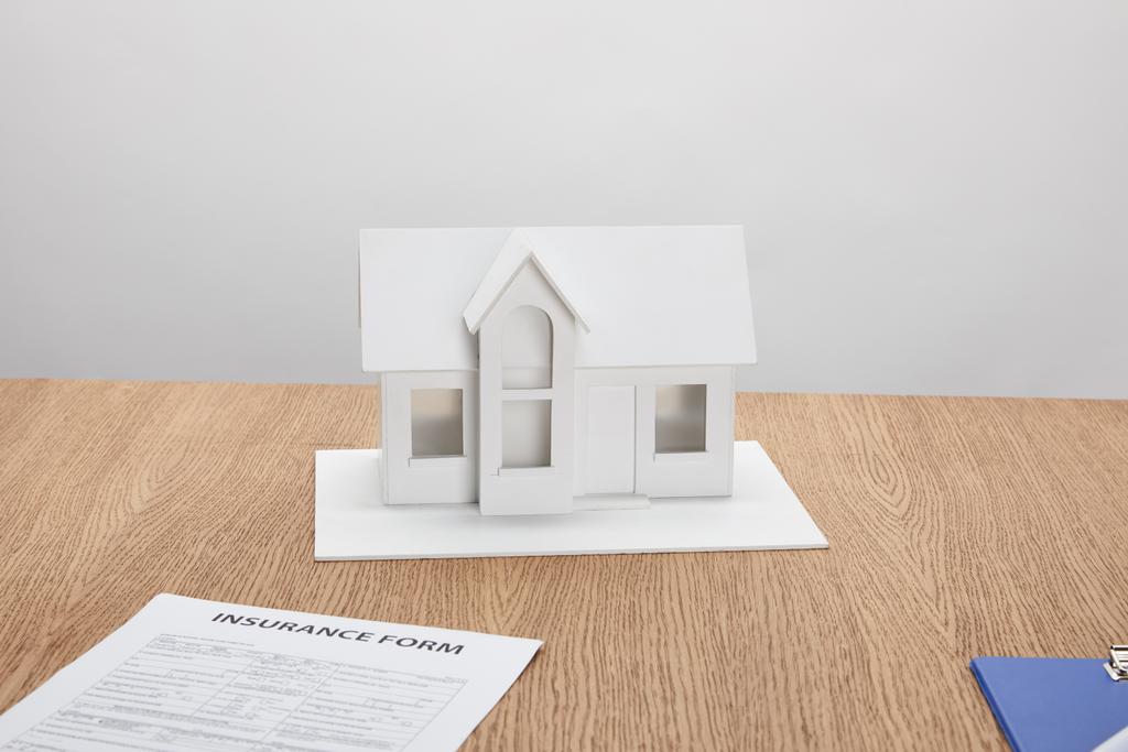 vista ravvicinata della forma assicurativa e del modello di piccola casa sul tavolo di legno
 - Foto, immagini