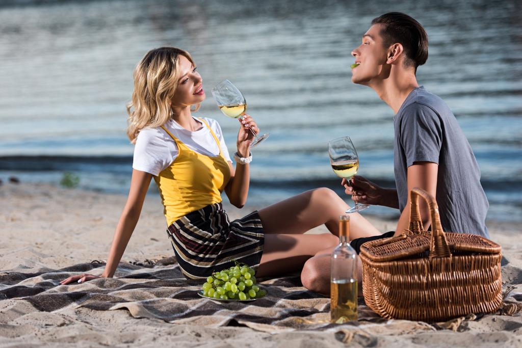 young couple having fun at picnic on river beach in evening - Photo, Image