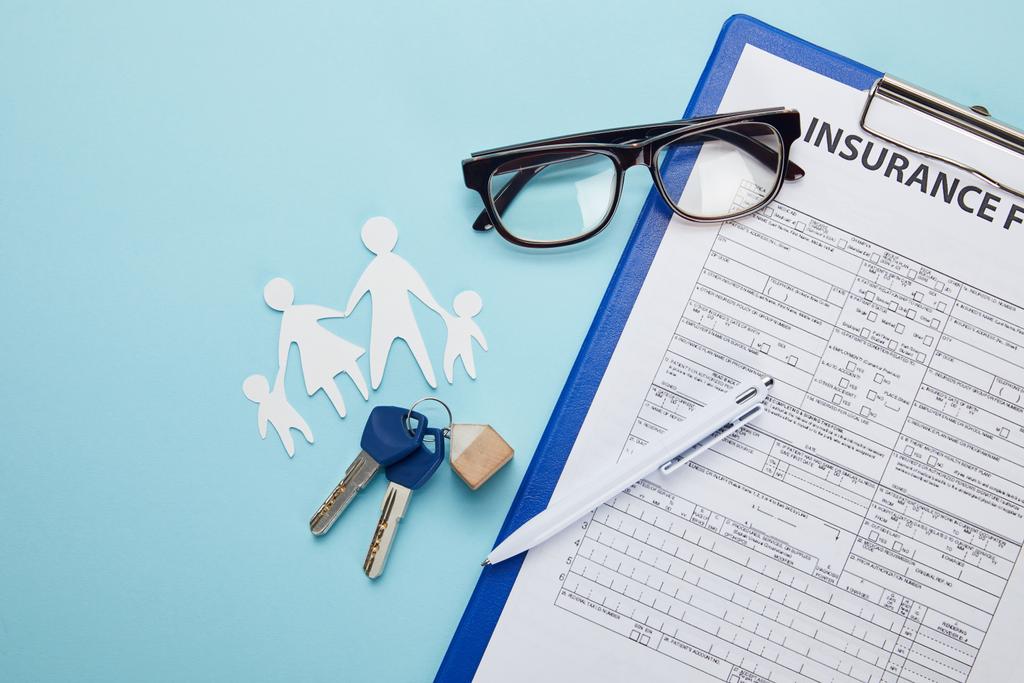 vista superior del formulario de seguro, lápiz, familia de corte de papel y llaves aisladas en azul
   - Foto, Imagen