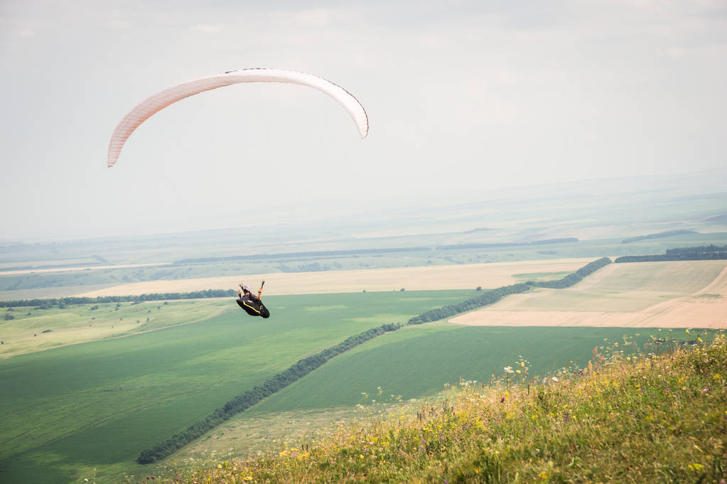 Wit oranje paragliden met een paraglider in een cocon tegen de achtergrond van het gebied van de lucht en de wolken. Paragliding sport - Foto, afbeelding