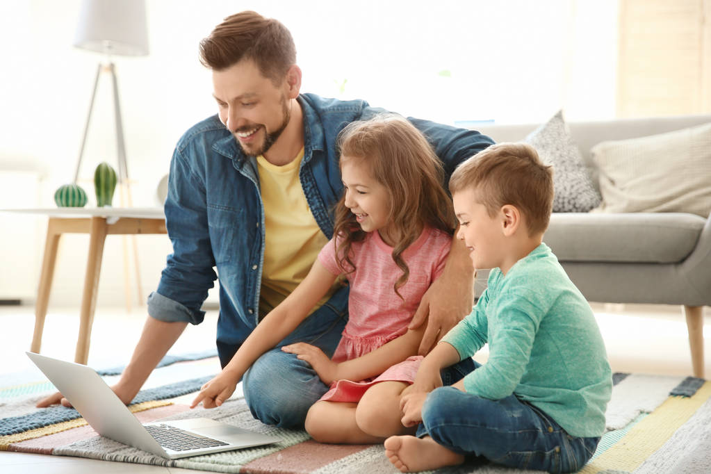自宅で子供にノート パソコンを使用しての若い男。幸せな家族 - 写真・画像