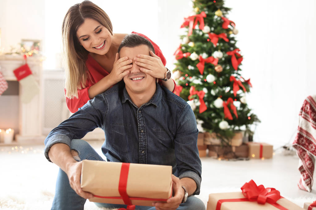 Jeune femme surprenant son petit ami avec cadeau de Noël à la maison
 - Photo, image