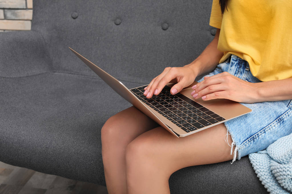 Młoda kobieta z nowoczesnym laptopie siedzi na kanapie w domu, zbliżenie - Zdjęcie, obraz