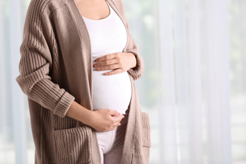 Έγκυος γυναίκα να στέκεται κοντά στο παράθυρο στο σπίτι, κοντινό πλάνο - Φωτογραφία, εικόνα