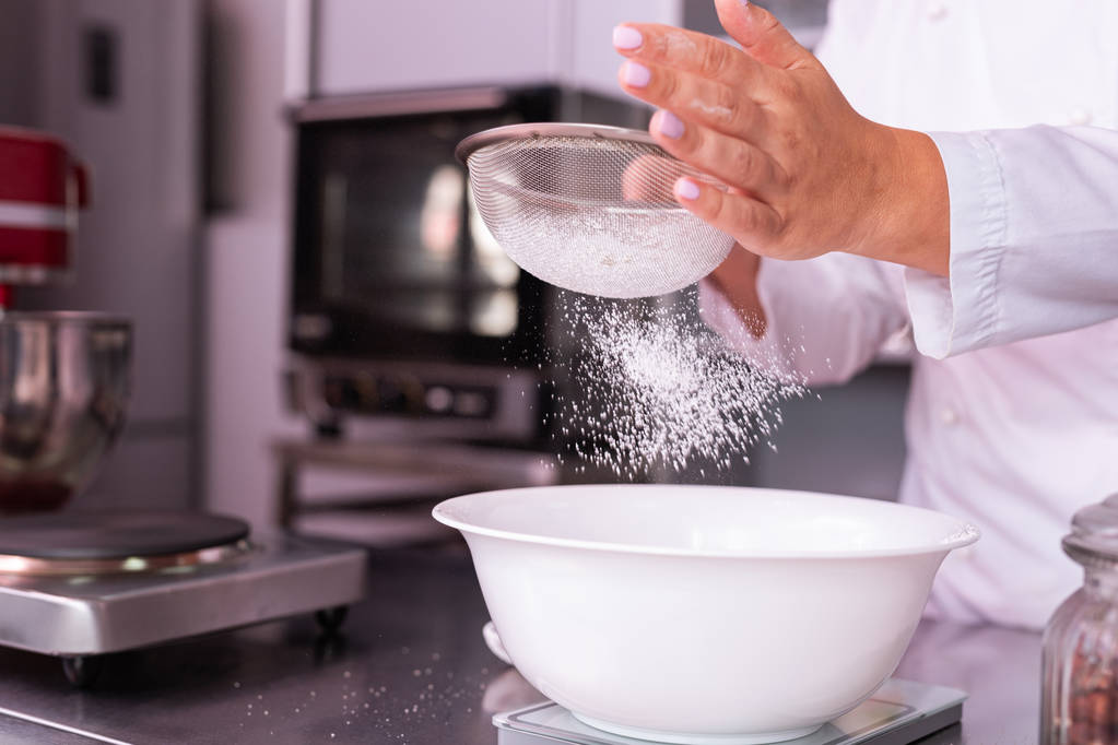 Szef kuchni z białym paznokcie przesiewania mąki podczas gotowania ładne duże ciasto - Zdjęcie, obraz