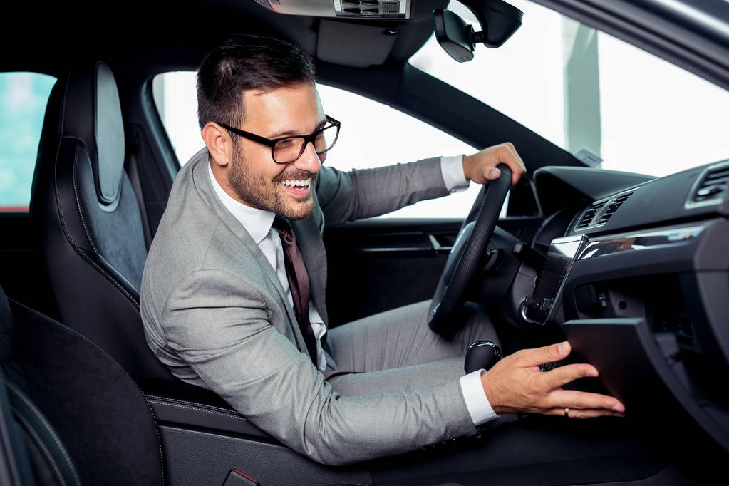 Красивий бізнесмен сидить у новій машині в автосалоні
 - Фото, зображення