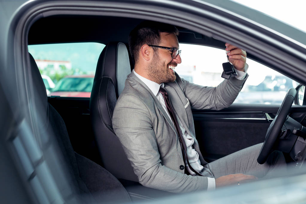 Knappe zakenman zit in een nieuwe auto in autodealer - Foto, afbeelding