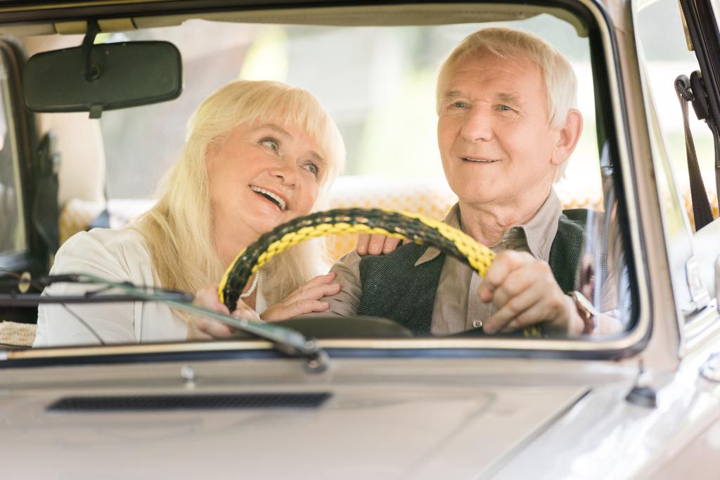 uśmiechający się starszy żona ogląda mąż jazda samochodem retro - Zdjęcie, obraz