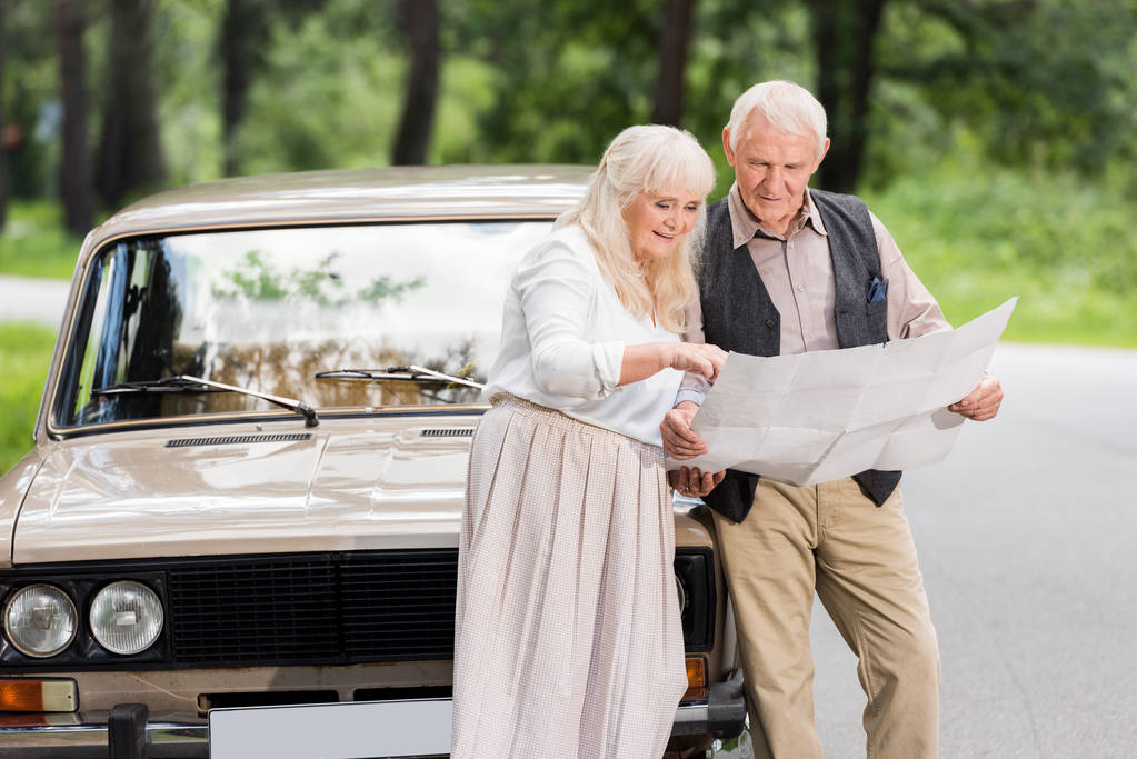 Senior Mann und Frau halten Karte und lehnen sich an Auto - Foto, Bild