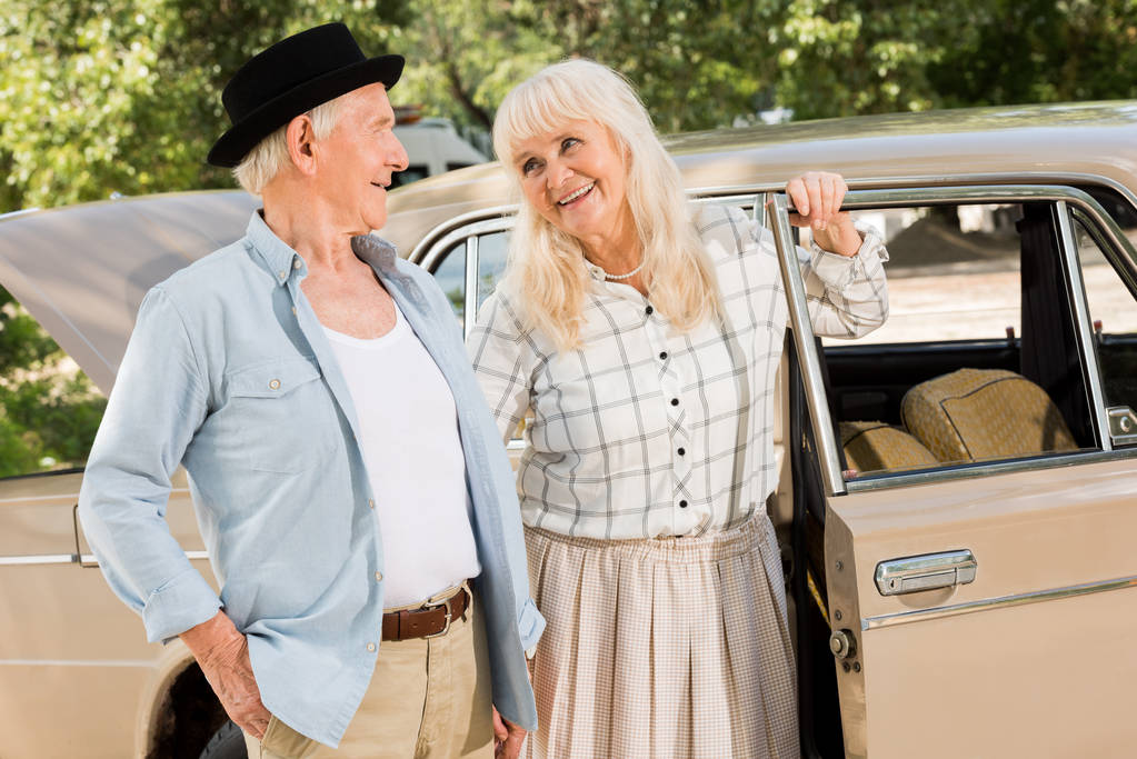 beau couple de personnes âgées debout près de voiture beige et se regardant
  - Photo, image