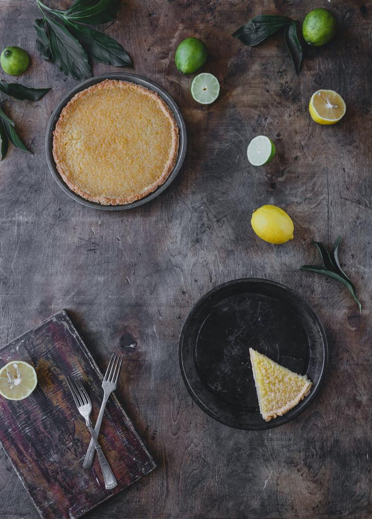木製のテーブルに美味しいレモンパイとレモンとライムの昇格を表示 - 写真・画像