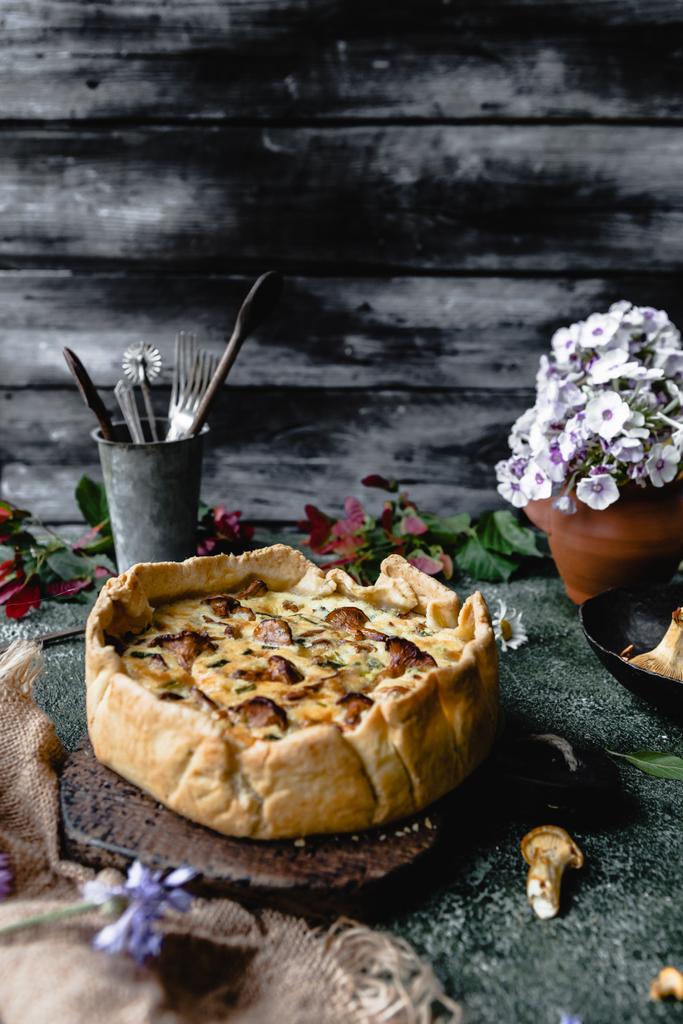 вкусный пирог с грибами и цветами в горшке на деревянном столе
 - Фото, изображение