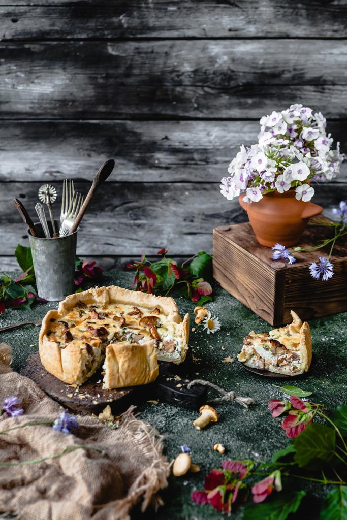 マッシュルームと木製のテーブルの上の鉢植えの花のおいしいパイ - 写真・画像