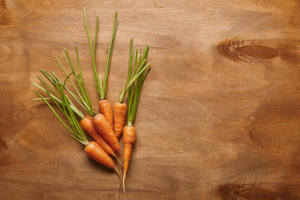 Куча сырой моркови на деревянном столе
 - Фото, изображение