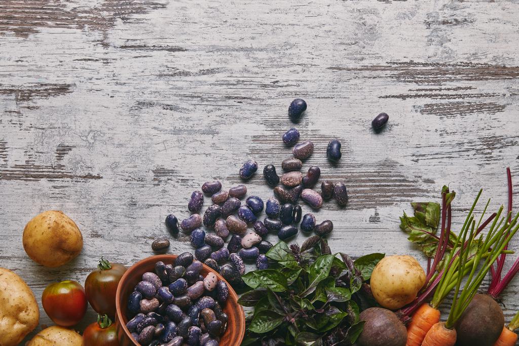 Fasola fioletowy i surowe warzywa do gotowania na rustykalne drewniany stół - Zdjęcie, obraz