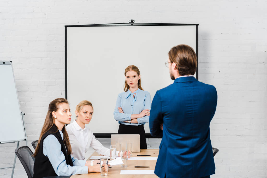 Achteraanzicht van baas aan managers te praten tijdens de bijeenkomst in moderne kantoren - Foto, afbeelding